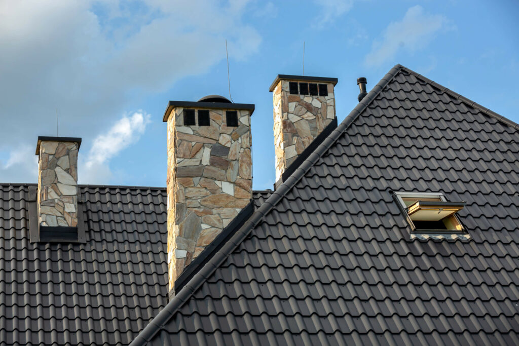 Log house in the mountains with a roof made of tiles and stone chimneys.