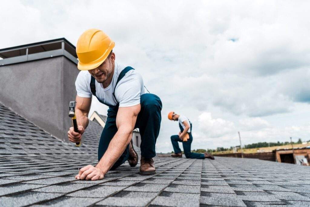 selective-focus-of-handyman-holding-hammer-while-repairing-roof-near-coworker.jpg