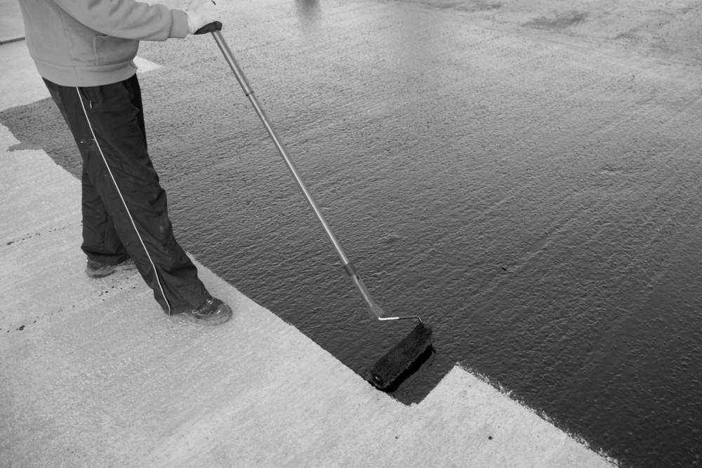 Worker applies bitumen mastic on the foundation