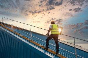 Worker with yellow helment and green vest doing Roof Inspection